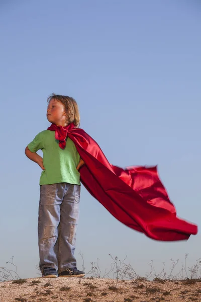 Мальчик, играющий в супергероев на фоне неба, подростковый супергерой — стоковое фото