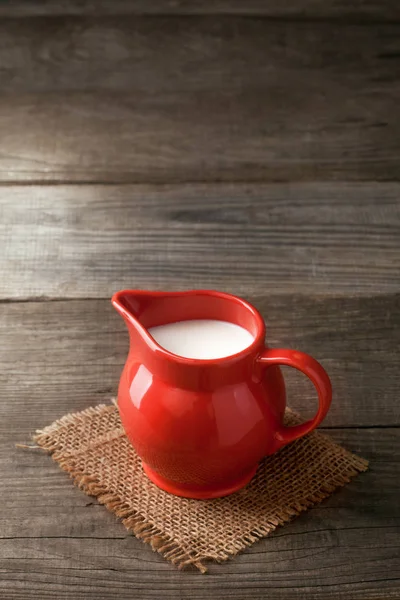 Latte in brocca di vetro su sfondo bianco tavolo di legno — Foto Stock