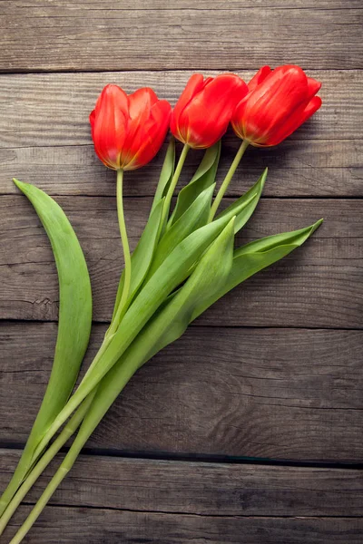 Czerwone tulipany na stare deski drewniane grunge widok z góry — Zdjęcie stockowe