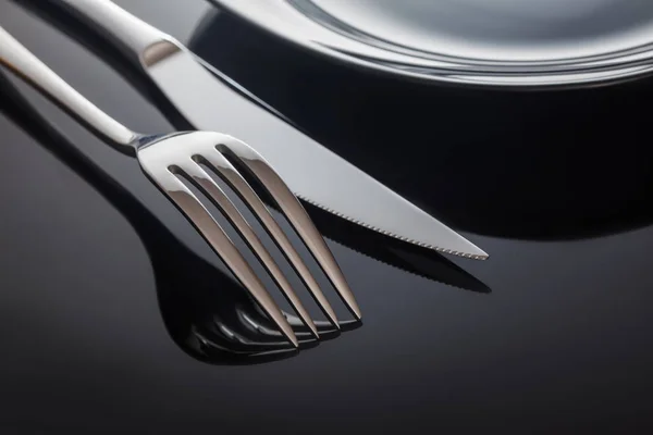 Placa vacía con cuchillo y tenedor sobre fondo negro — Foto de Stock