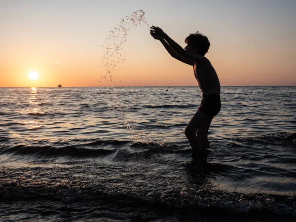 Garçon éclaboussant dans la mer les bras levés. Jeux d'enfants — Photo