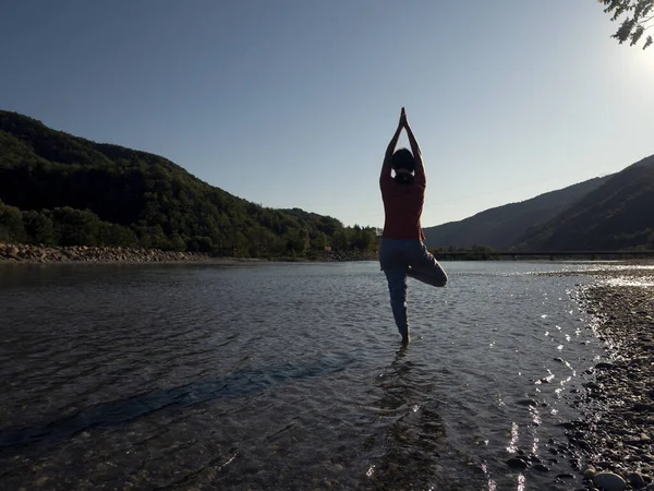 年轻女子正在高山湖畔的荷花中练习瑜伽 — 图库照片