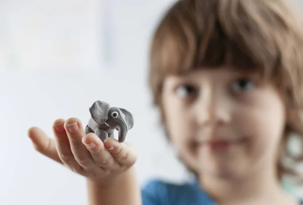 Söt liten pojke med elefant från plasticine på handen — Stockfoto