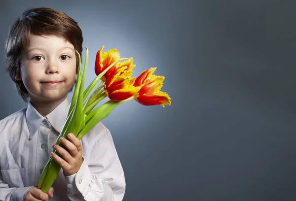 Ragazzo sorridente con fiori rossi Mazzo di tulipani per la mamma Spring Conce — Foto Stock
