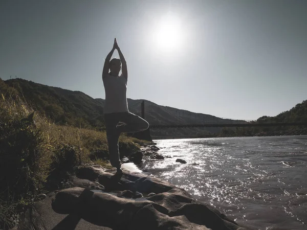 Jovem está praticando ioga em pose de lótus no lago da montanha — Fotografia de Stock