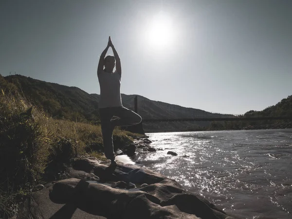 Junge Frau praktiziert Yoga in Lotus-Pose am Bergsee — Stockfoto