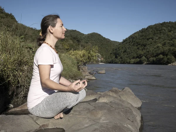 Genç kadın dağ gölünde lotus poz vererek yoga yapıyor. — Stok fotoğraf