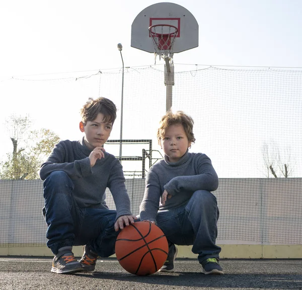 Два счастливых молодых мальчика играют в баскетбол на свежем воздухе на спортивном огне — стоковое фото