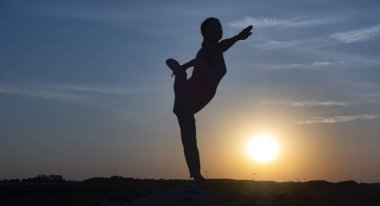 Genç kadın dağda natarajasana pozuyla yoga yapıyor. 