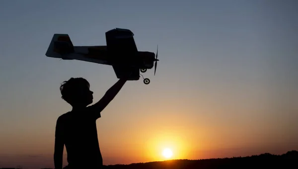 Happy Boy corre com um avião de brinquedo em um campo ao pôr-do-sol — Fotografia de Stock