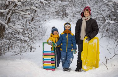 Kızaklı üç mutlu çocuk ve açık havada kış ormanlarında kayak. Chi