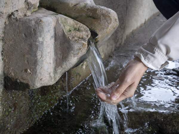 Woman hand pouring Water on nature spring.