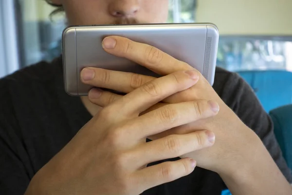 La parte trasera de un teléfono inteligente, sostenido por la mano de un adolescente en Ca — Foto de Stock