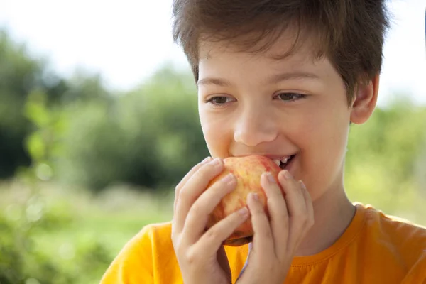 Egy gyümölcsös gyerek. Friss körtét eszik. Boldog fiú harapás ap — Stock Fotó