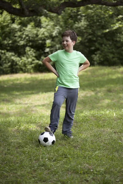 Niño adolescente futbolista. Niño de fútbol con pelota sobre hierba verde . — Foto de Stock