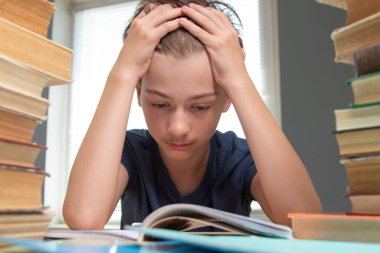 Ödevle ders kitabına bakan üzgün okul çocuğunun portresi.