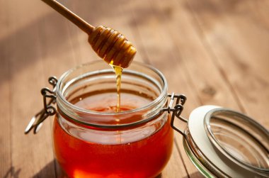 Ahşap zeminde cam kavanozda bal.