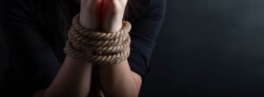 woman hands tied with a coarse rope close-up black background clipart