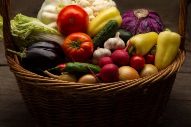 Farklı organik meyve ve sebzeler ahşap masanın arkasında sepette..