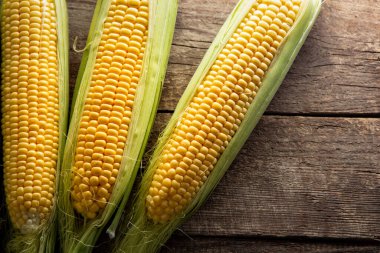Eski ahşap masada taze mısır, üst manzara, yakın çekim.
