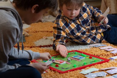 Belgorod, Rusya - APR, 20, 2020: Çocuklar yerde Scrabble oynuyor. Masa oyunu çipleri bulmacada gizlidir. Eğitim, eğlence konsepti Okula geri dönüş