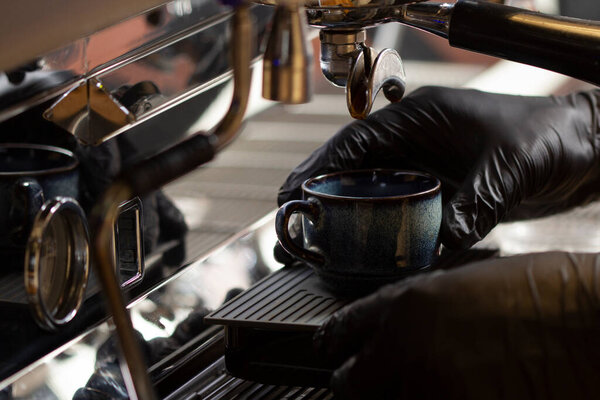 бариста варит кофе с помощью современной кофемашины.
