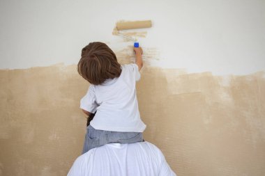 Baba oğluna yeni evde duvar boyamasında yardım ediyor.