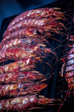 Karides royal, ızgara. Karides üzerinde sıcak bir mangal dumanı tüten apetisant. Bir siyah ızgara karides kavrulmuş.