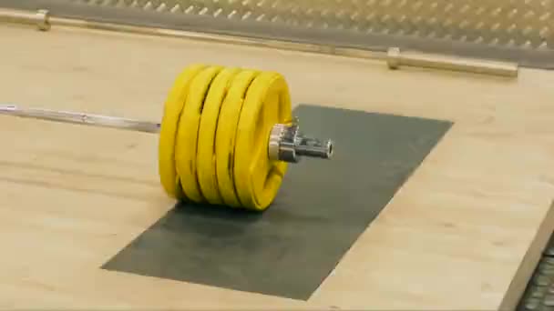 在健身房的木地板上有黄色重量的杠铃 相机沿着杠铃平滑地移动 — 图库视频影像