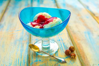 Mavi kase dondurma ve kurulların ahşap arka plan üzerinde kırmızı reçel ile