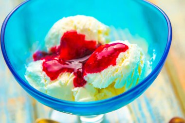 Mavi kase dondurma ve kurulların ahşap arka plan üzerinde kırmızı reçel ile