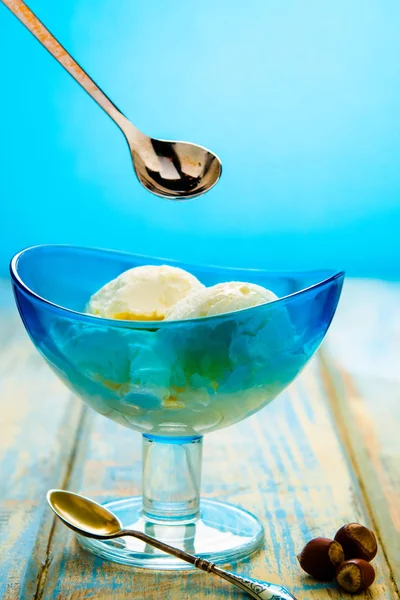 Blue bowl with ice cream and with red jam on a wooden background of boards