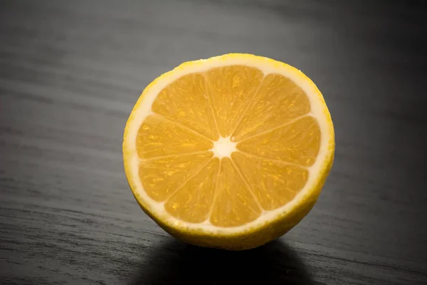 Limón Amarillo Recién Cortado Por Mitad Contra Una Mesa Negra — Foto de Stock