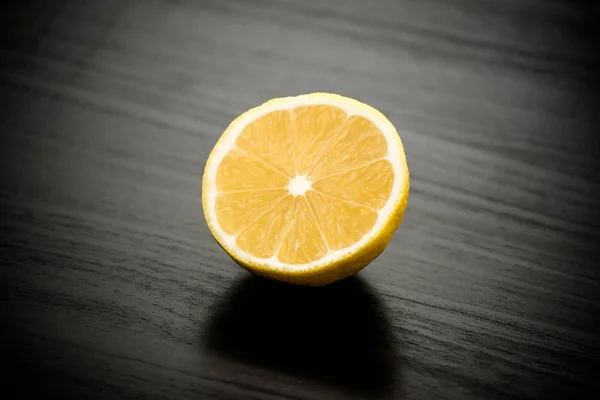 Limón Amarillo Recién Cortado Por Mitad Contra Una Mesa Negra — Foto de Stock