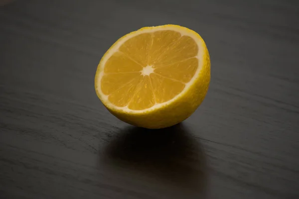 Limón Amarillo Recién Cortado Por Mitad Contra Una Mesa Negra — Foto de Stock