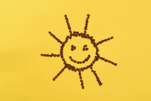 Grappig en schattig zon van koffiebonen, op een gele achtergrond — Stockfoto