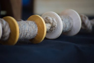 Ahşap iplik ya da ip makaraları koyu renk bir kumaşın üzerinde yatar. El yapımı. Efsane laboratuarında dikiş dikiyorum..