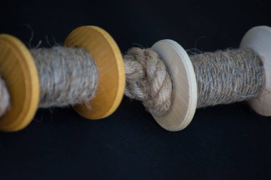 Ahşap iplik ya da ip makaraları koyu renk bir kumaşın üzerinde yatar. El yapımı. Efsane laboratuarında dikiş dikiyorum..