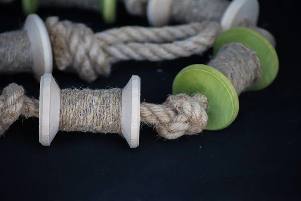 Деревянные катушки ниток или веревки лежат на темной ткани. Сделано вручную. Шитье в ткани . — стоковое фото