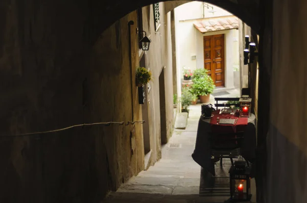 A romantic table for two outside a restaurant in a narrow cobblestone alley in the historic centre of Cortona, Tuscany, Italy, Europe