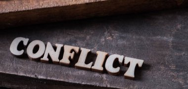 Ahşap arka plan üzerinde 'Çatışma' metin.