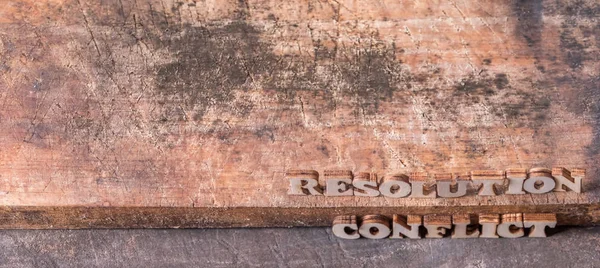 \'RESOLUTION\' and \'CONFLICT\' text on wooden background.