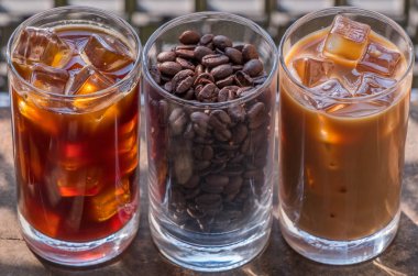 Ahşap arka plan üzerinde siyah kahve, süt kahve ve fasulye buzlu