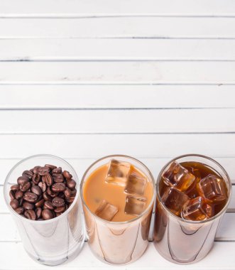 Ahşap arka plan üzerinde siyah kahve, soğuk latte ve fasulye buzlu