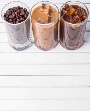 Ahşap arka plan üzerinde siyah kahve, soğuk latte ve fasulye buzlu