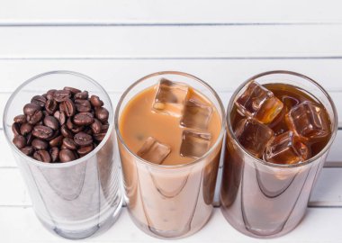 Ahşap arka plan üzerinde siyah kahve, soğuk latte ve fasulye buzlu