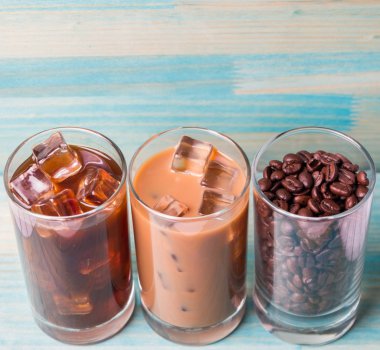 Ahşap arka plan üzerinde siyah kahve, soğuk latte ve fasulye buzlu