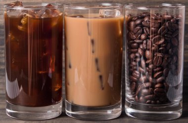 Ahşap arka plan üzerinde siyah kahve, soğuk latte ve fasulye buzlu