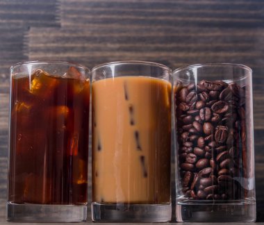 Ahşap arka plan üzerinde siyah kahve, soğuk latte ve fasulye buzlu