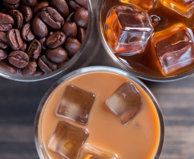 Ahşap arka plan üzerinde siyah kahve, soğuk latte ve fasulye buzlu